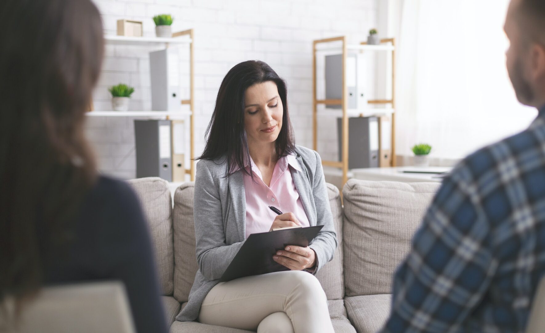 Professional psychologist taking notes at couple meeting with patients